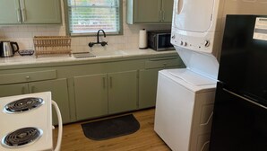A kitchen with green cabinets, a white stove, a microwave, and a washing machine.