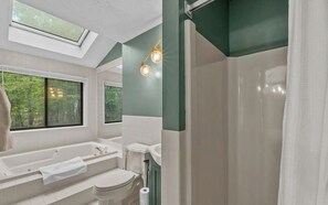 A modern bathroom with a skylight, a bathtub, a shower, and a toilet. - Poconos Home with Hot Tub and Game Loft (East Stroudsburg)