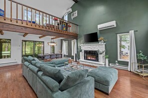 Comfortable sectional seating faces the fireplace in the main living room. - Wooded Poconos Retreat - Hot Tub & Game Loft (East Stroudsburg)