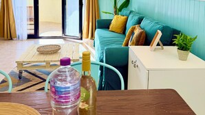 Una sala de estar con un sofá azul verdoso, una mesa de centro de madera, un mueble blanco pequeño y una planta en maceta.