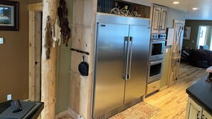 Una cocina moderna con un refrigerador de acero inoxidable, armarios de madera y un horno empotrado.