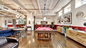 Ein geräumiges Zimmer mit Billardtisch, Ledersitzmöbeln und einer Billard-Ecke.