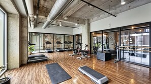 A gym with treadmills, weights, and a wooden floor. - Downtown Dallas Gem - 1000Mbps Fiber, Free Valet & Pool (Dallas)
