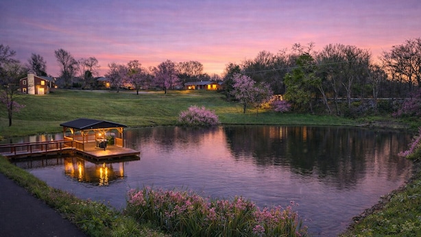Un cadre paisible au bord d’un lac, avec une jetée et un pavillon en bois, le tout entouré d’arbres en fleurs et d’une étendue d’eau calme.