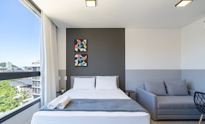 A modern hotel room with a large bed, a grey sofa, and two abstract paintings on the wall. - Studio 150m From Jurere Beach Pte0507 (Florianópolis)