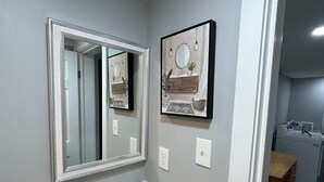Een badkamer met een witte wastafel, een spiegel en een lijst met een foto aan de muur.