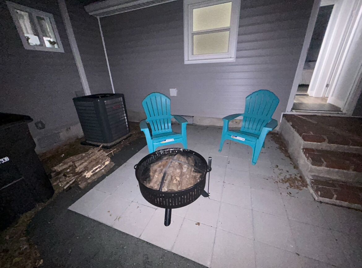 Un patio con dos sillas Adirondack turquesa, una parrilla negra y un bote de basura.