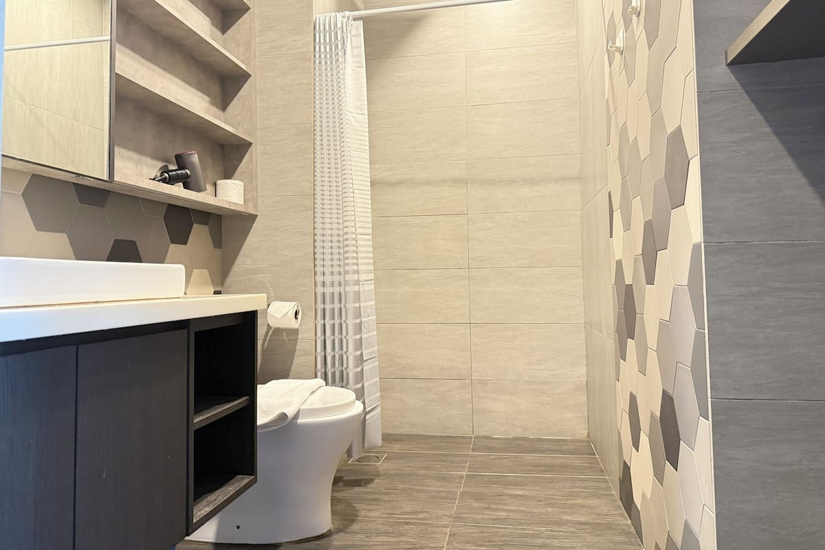 A modern bathroom with a toilet, shower, and storage shelves.