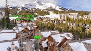 A resort area with wooden buildings, a ski slope, and a mountain in the background. - Ski In/Out | Black Eagle Base-Inn | Big Sky Resort (Big Sky)