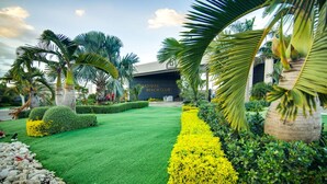 Ein gepflegter Garten mit einem Weg, der zu einem Gebäude mit der Aufschrift "RADISIAC BEACH CLUB" führt.