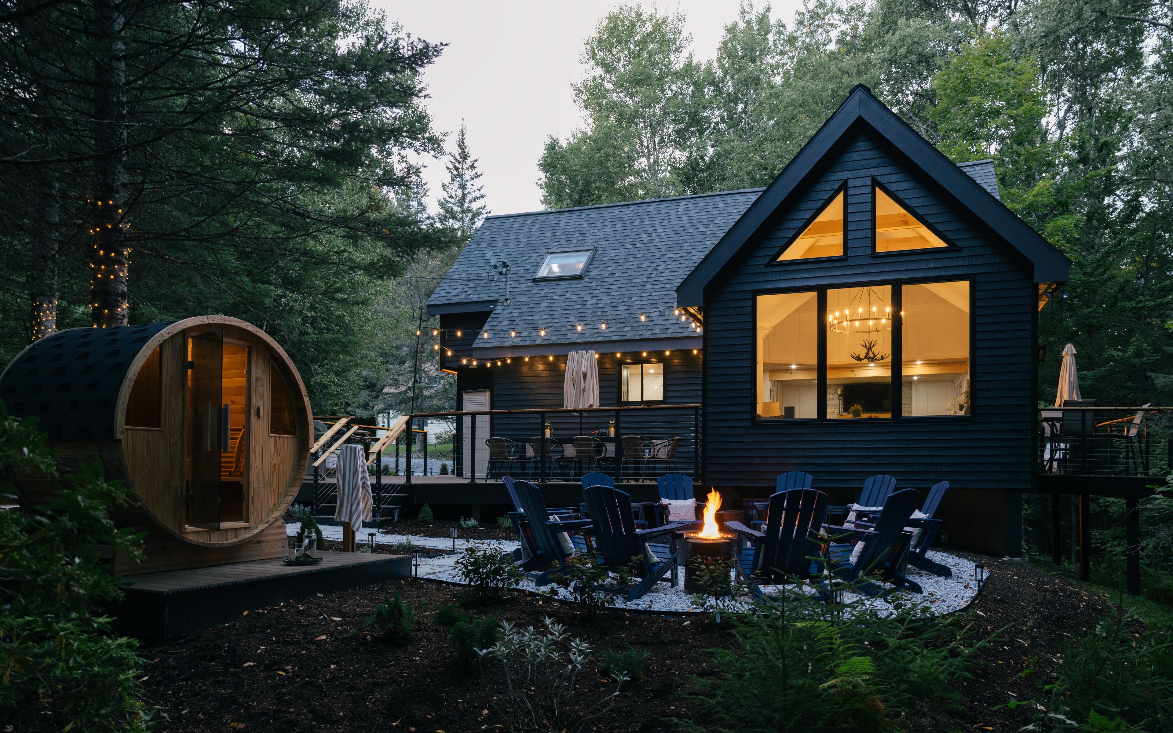 Eine Hütte mit einer Terrasse, Sitzgelegenheiten im Freien und einer Feuerstelle.
