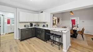 Una cucina moderna con pensili scuri, un'isola bianca e un'area pranzo con sedie in legno.