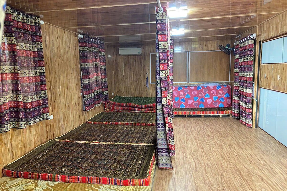 A room with a large bed, wooden walls, and patterned curtains.