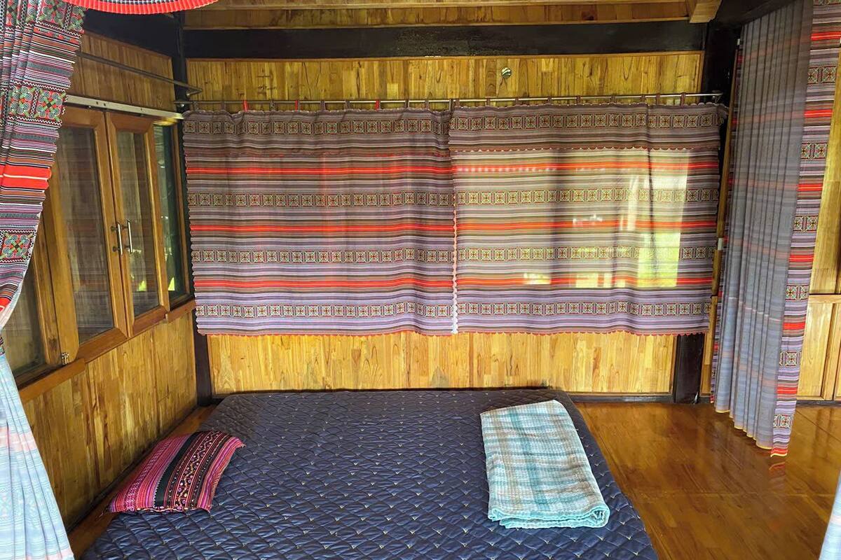 A room with a bed, wooden walls, and patterned curtains.