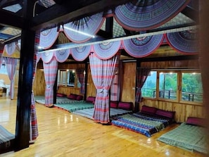 Une pièce avec un plancher en bois, un lit recouvert d’une couvre-lit à motifs et des rideaux ornés d’un motif circulaire.