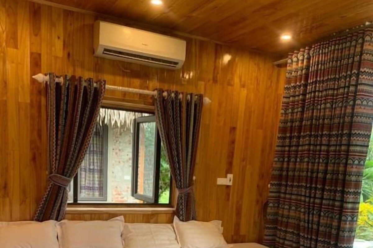 Una stanza con pannelli in legno, un letto grande, una finestra con tende e un condizionatore d'aria.