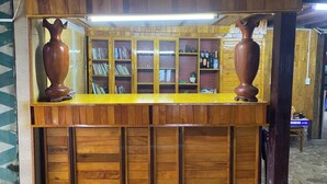 A wooden reception desk with two large vases on top, surrounded by bookshelves and a counter.