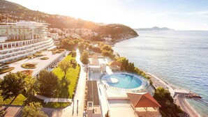 Een resort met een groot zwembad, een strand en een bergachtige achtergrond.