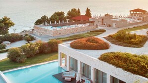 Een modern hotel met een zwembad op het dak, een overdekt terras en uitzicht op zee.