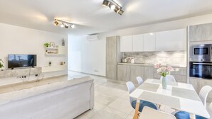 Een moderne keuken met witte kasten, een inbouwoven en een magnetron.