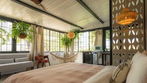 Un dormitorio con una cama grande, una hamaca y un escritorio con una computadora.