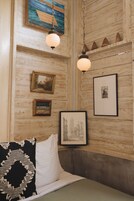 A room with wooden walls, a bed with a striped pillow, and framed artwork.
