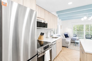 A modern kitchen with stainless steel appliances, a microwave, and a dining area with a sofa and chairs. - Charming Sanibel condo - Easy walk to the beach - Pool - Colony Inn 02 (Sanibel)