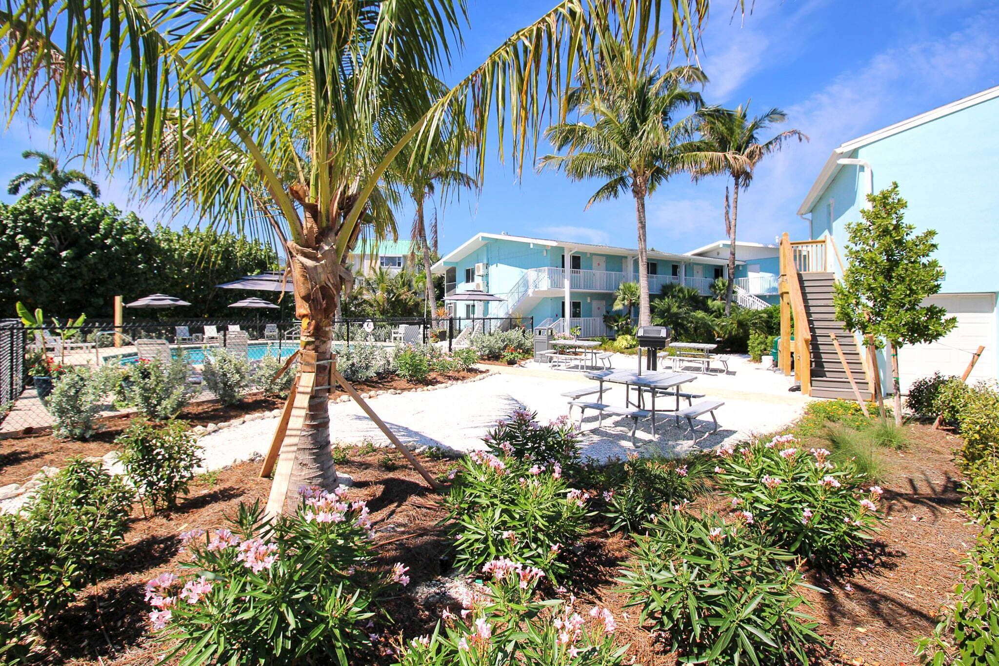 A resort with a pool, palm trees, and a patio area with tables and chairs.