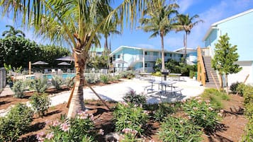 A resort with a pool, palm trees, and a patio area with tables and chairs.