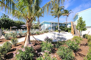 A resort with a pool, palm trees, and a patio area with tables and chairs. - Cozy 1BR Sanibel Beach Condo - Colony Inn 04 (Sanibel)