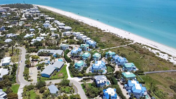 An aerial view of a coastal residential area with houses, a beach, and boats. - Sunny 1BR Sanibel Island Escape - Colony Inn 06 (Sanibel)
