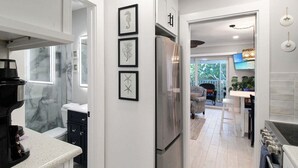 A modern kitchen with a built-in refrigerator, a coffee maker, and framed artwork on the wall. - Relaxing 1BR Sanibel Hideaway - Colony Inn 13 (Sanibel)