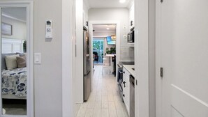 A narrow hallway leading to a kitchen with white cabinets and a dining area. - Relaxing 1BR Sanibel Hideaway - Colony Inn 13 (Sanibel)