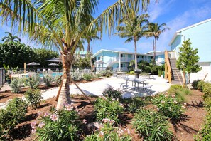 Ein Resort mit Pool, Palmen und einer Terrasse mit Tischen und Stühlen.