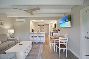 A modern living room with a sofa, coffee table, and dining area with chairs and a table. - 1BR - Short walk to the beach - Colony Inn 46 (Sanibel)