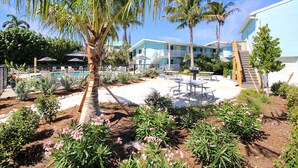 Ein Resort mit Pool, Palmen und einer Terrasse mit Tischen und Stühlen.