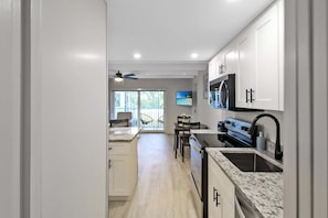 Eine moderne Küche mit weißen Schränken, einer Arbeitsplatte aus Granit und einem eingebauten Backofen.
