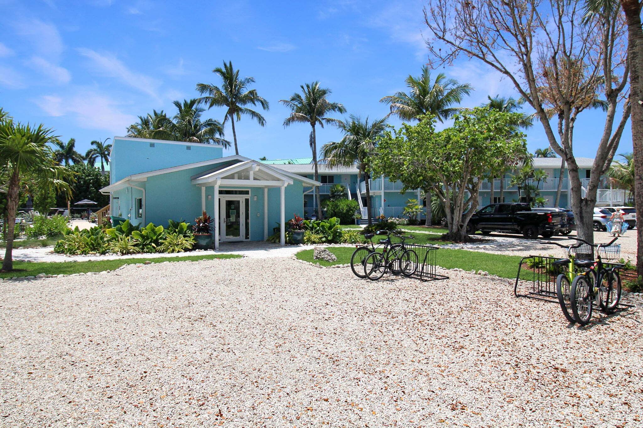 A building with a blue exterior, a gravel driveway, and bicycles parked outside.