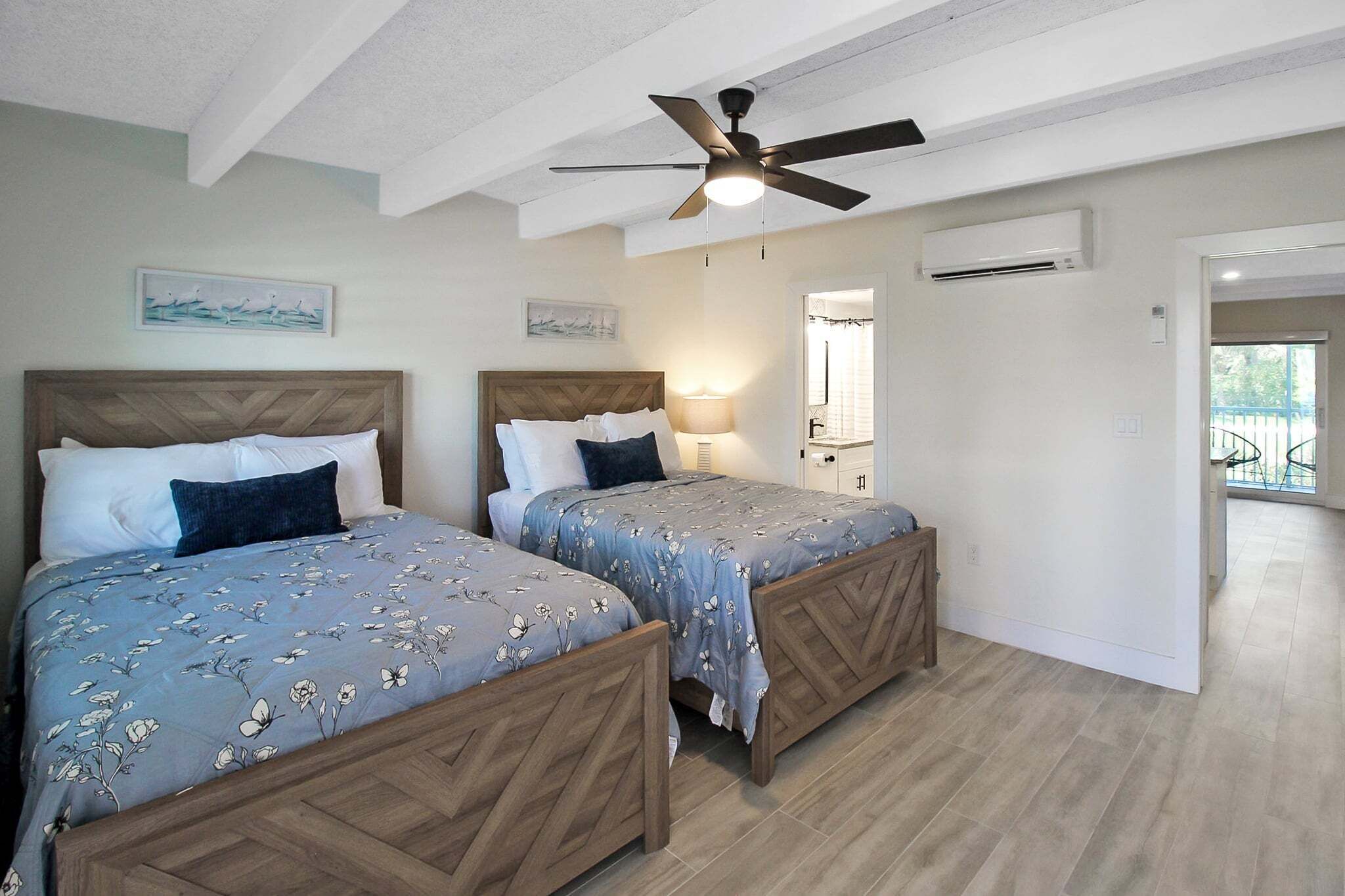 Un dormitorio con dos camas, ventilador de techo y aire acondicionado.