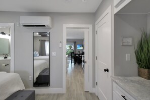 Ett modernt hotellrum med en säng, ett sängbord, en spegel, en luftkonditioneringsanläggning och utsikt över matsalen.