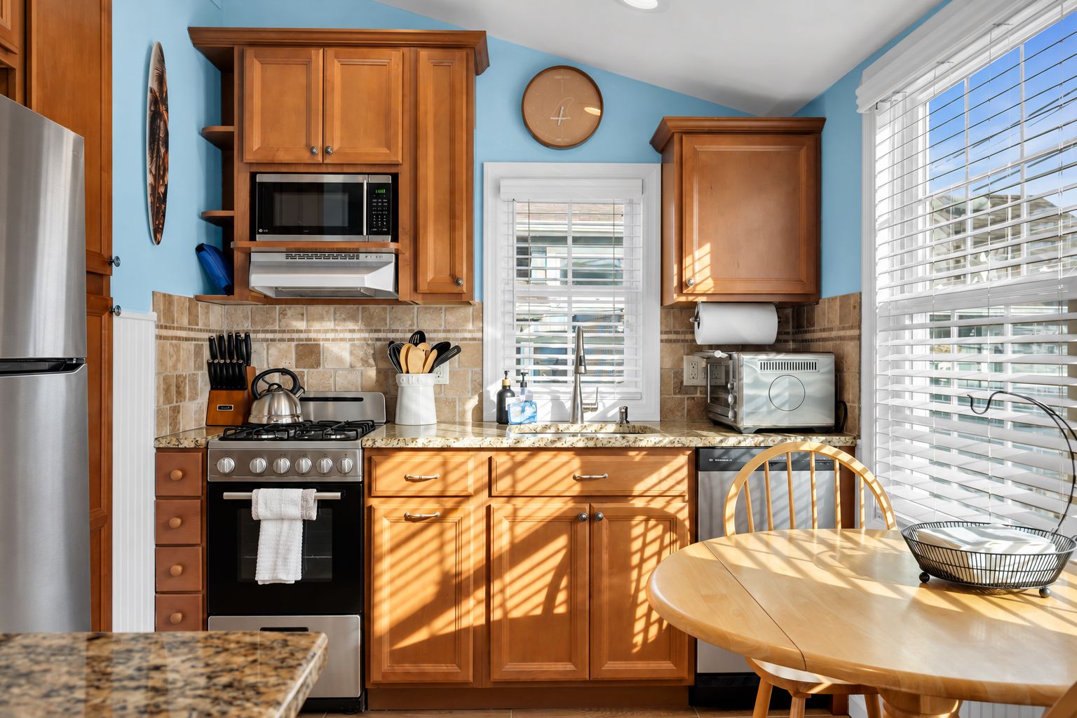 Full kitchen with gas range, microwave, marble counters, and dinette seating.