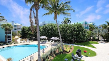 A swimming pool with lounge chairs, palm trees, and a well-maintained lawn.