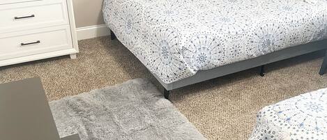 A bedroom with a bed, a dresser, and a rug.