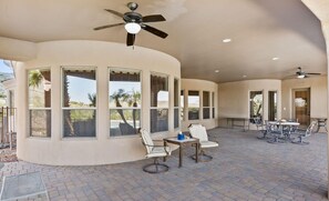 A covered patio area with a curved wall, large windows, and outdoor furniture.