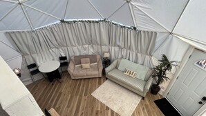 Una habitación con tienda de campaña, un sofá, una mesita y sillas.