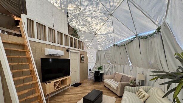 Un espacio de estar con carpa, que incluye televisor, sofá y piso de madera.