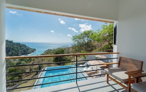 Un balcón con vista a una piscina y al océano.