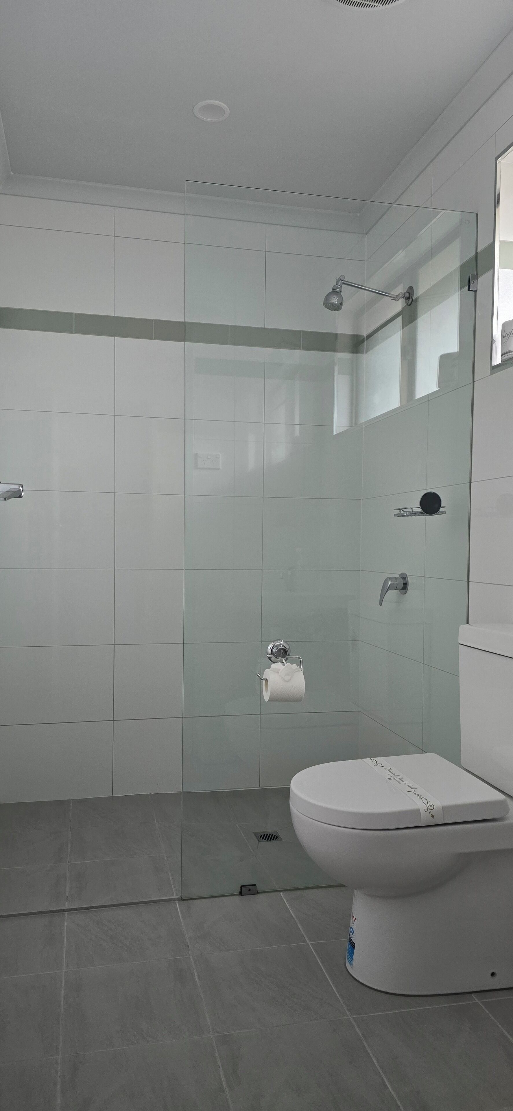 Un bagno moderno con cabina doccia in vetro, un water e un lavabo.