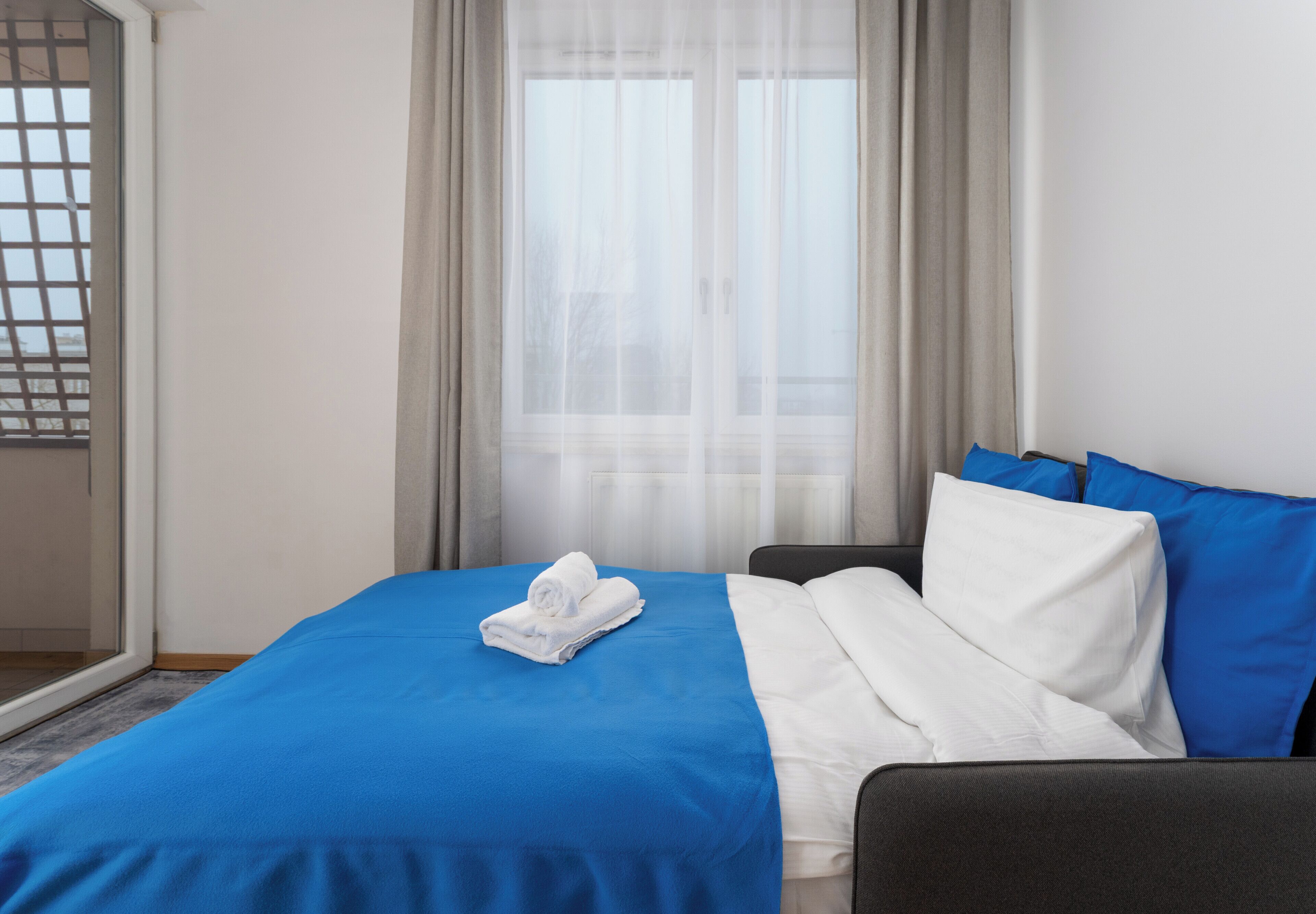 Ein Hotelzimmer mit Bett, einem Fenster mit Vorhängen und Blick nach draußen.