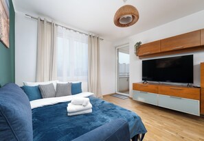 Quarto moderno com cama grande, televisão de tela plana, armários de madeira e vista para a cidade.